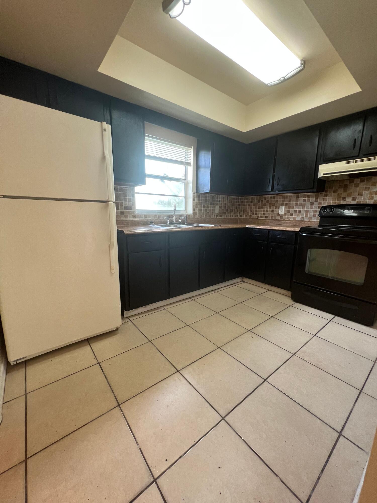 a kitchen with granite countertop a refrigerator a sink a stove top oven and cabinets