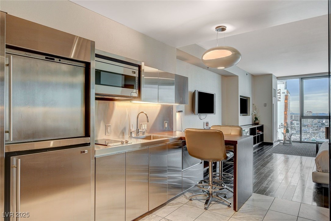 4381 West Flamingo Road, Unit 2204 Las Vegas, NV 89103 - Photo 15 of 27 Kitchen featuring stainless steel microwave, expansive windows, modern cabinets, pendant lighting, and stovetop