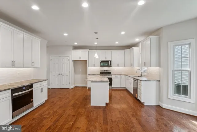 an empty room with wooden floor chandelier fan and windows