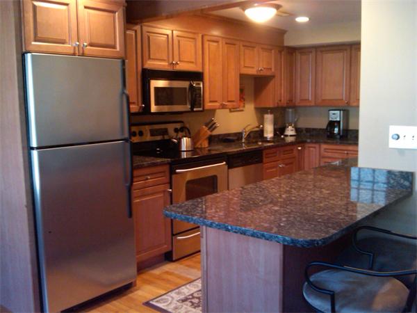 88 Jericho Road, Unit 88 Weston, MA 02493 - Photo 2 of 8 a kitchen with stainless steel appliances granite countertop a refrigerator stove microwave and sink