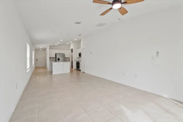 a view of a livingroom with a ceiling fan and kitchen view