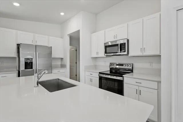 a kitchen with stainless steel appliances a stove a sink a microwave a refrigerator and cabinets