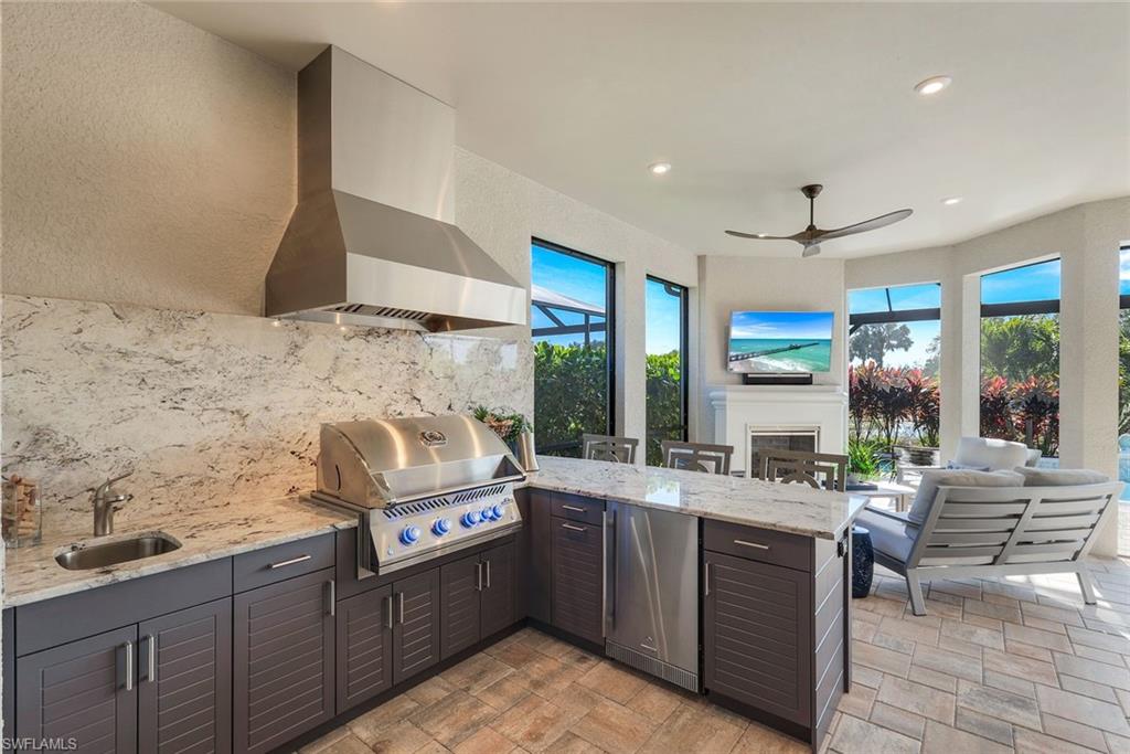 8935 Cappello Court Naples, FL 34119 - Photo 22 of 50 a large kitchen with kitchen island granite countertop a sink and a stove top oven
