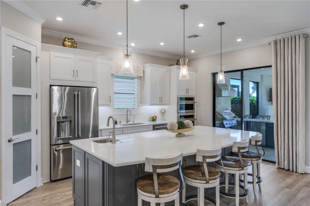 8935 Cappello Court Naples, FL 34119 - Photo 7 of 50 a kitchen with stainless steel appliances kitchen island granite countertop a kitchen island hardwood floor and a sink