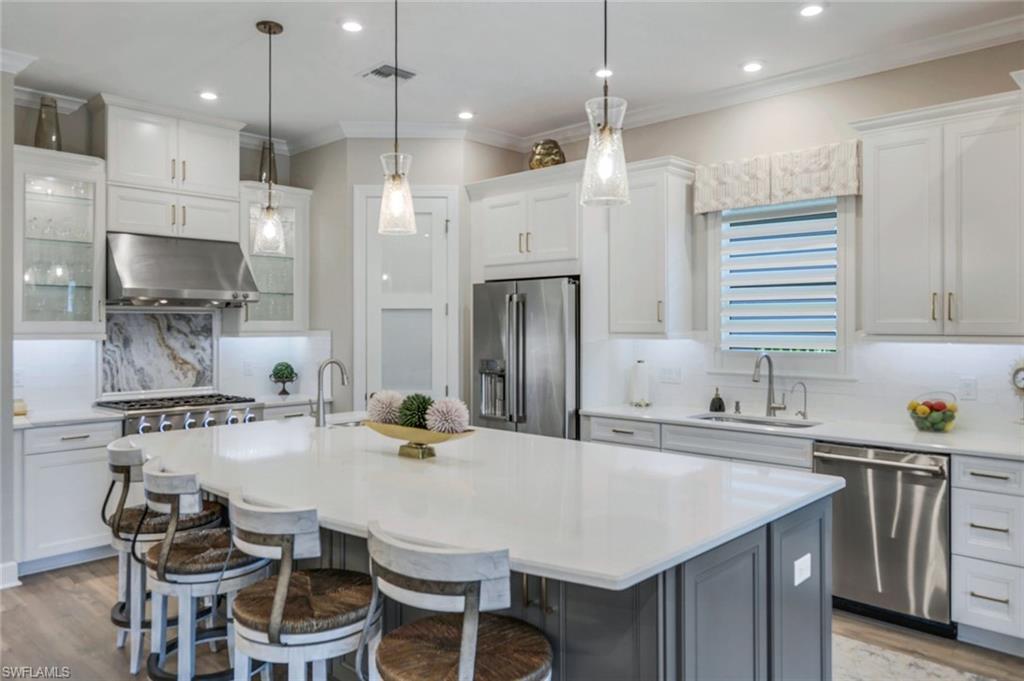 8935 Cappello Court Naples, FL 34119 - Photo 8 of 50 a kitchen with stainless steel appliances kitchen island a table chairs in it and wooden floors