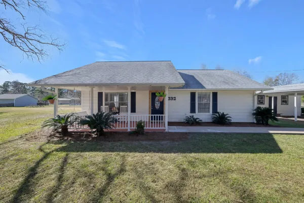 a front view of a house with a yard outdoor seating and covered with trees