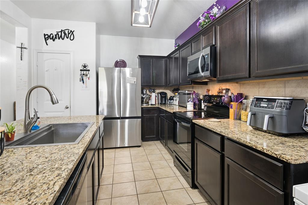 324 Fairgrounds Lane Ponder, TX 76259 - Photo 9 of 40 a kitchen with granite countertop a sink stainless steel appliances and cabinets