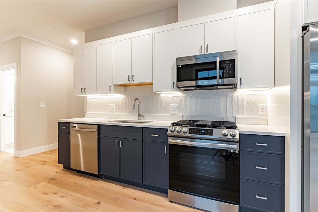 157 Everett Street, Unit 302 Boston, MA 02134 - Photo 2 of 11 a kitchen with stainless steel appliances granite countertop a stove microwave and sink