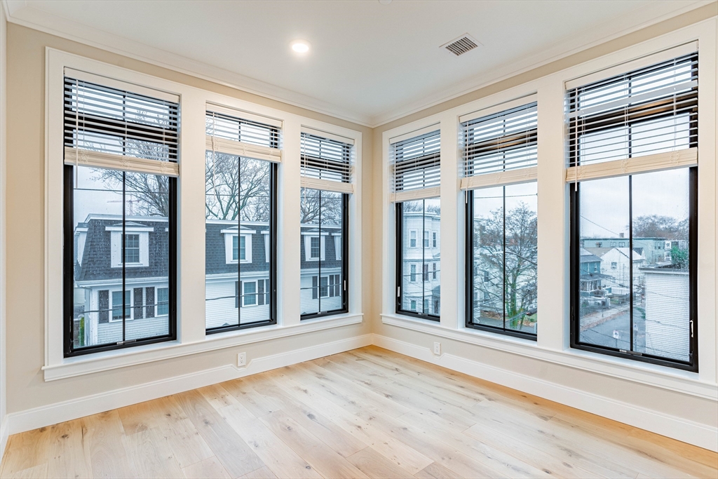 157 Everett Street, Unit 302 Boston, MA 02134 - Photo 3 of 11 a view of an empty room with wooden floor and a window