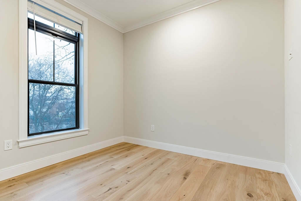 157 Everett Street, Unit 302 Boston, MA 02134 - Photo 5 of 11 an empty room with wooden floor and windows