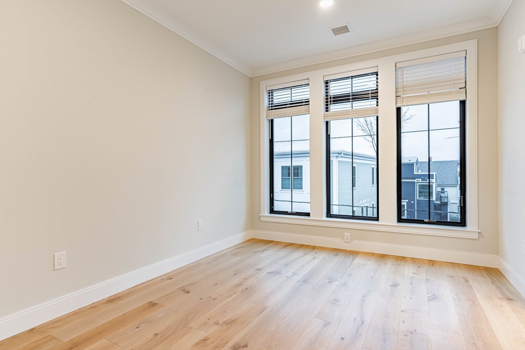 157 Everett Street, Unit 302 Boston, MA 02134 - Photo 7 of 11 an empty room with wooden floor and windows