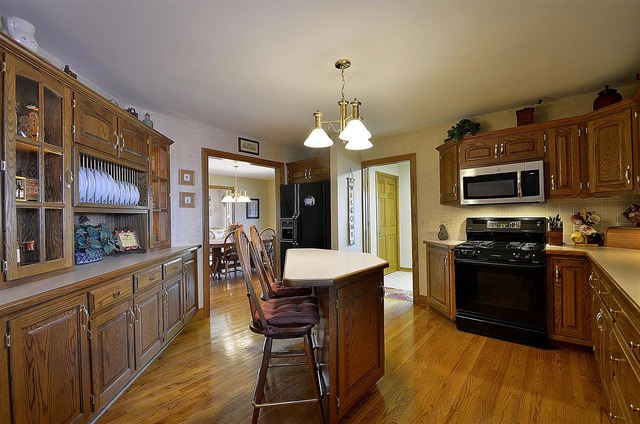 6-n034 Corron Road St. Charles, IL 60175 - Photo 9 of 25 a kitchen with stainless steel appliances kitchen island granite countertop a stove top oven a sink dishwasher a dining table and chairs with wooden floor