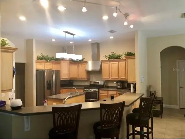 a kitchen with stainless steel appliances a dining table chairs and a refrigerator