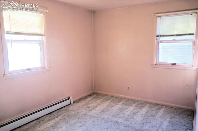 a view of an empty room with closet and a window