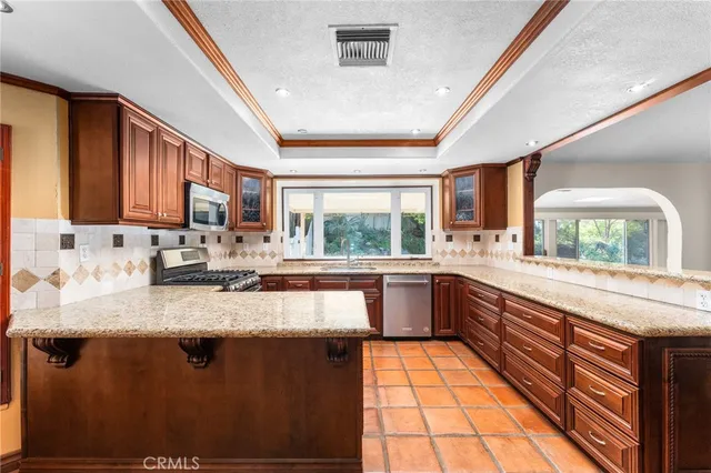 a large kitchen with stainless steel appliances granite countertop a stove refrigerator and a sink