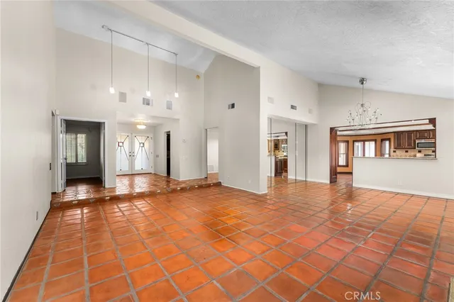 a view of an empty room with window and chandelier