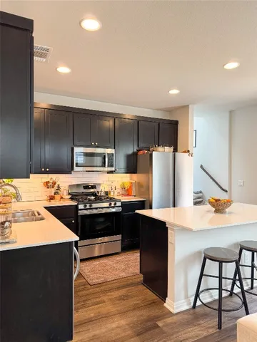 a kitchen with stainless steel appliances kitchen island granite countertop a refrigerator and a stove top oven