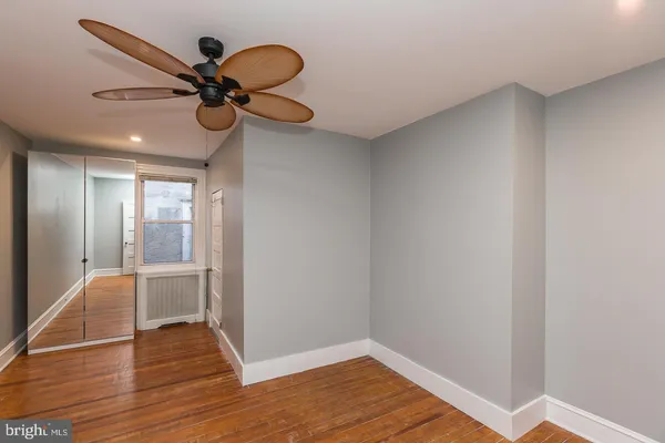 a view of a room with wooden floor and a ceiling fan