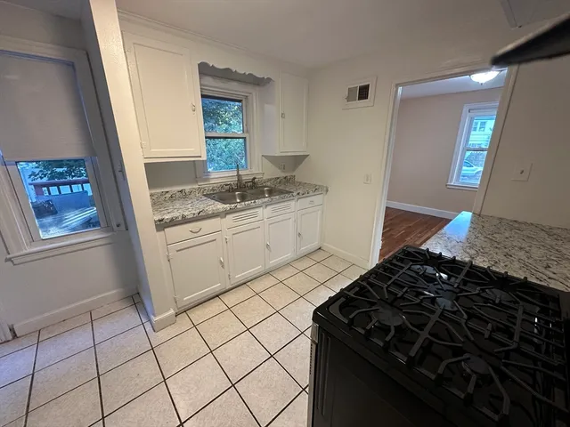 a kitchen with granite countertop white cabinets and a stove