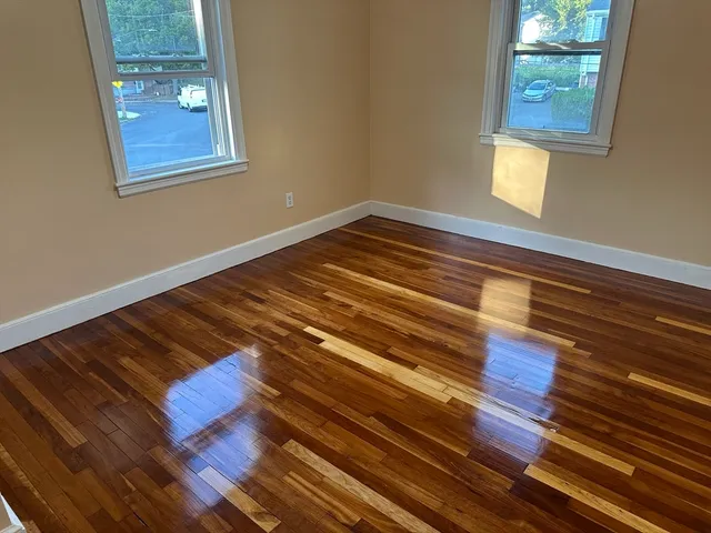 a view of an empty room with wooden floor and a window