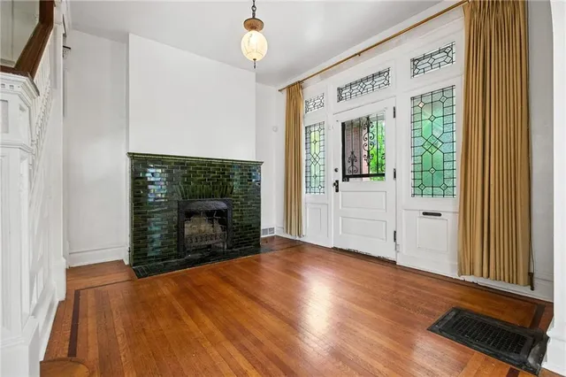 an empty room with wooden floor fireplace and windows