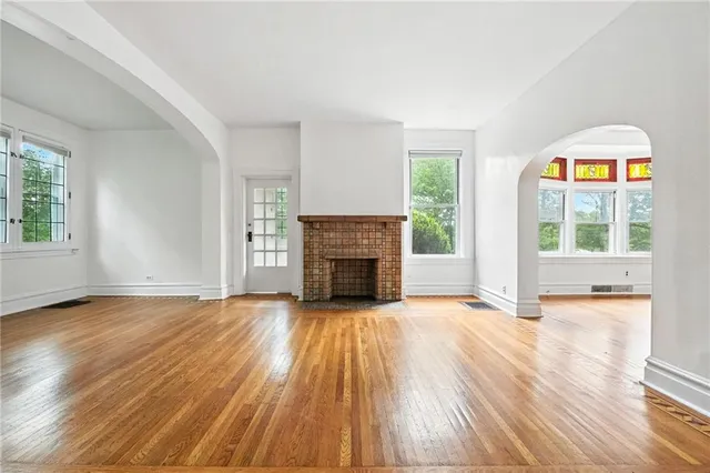 an empty room with windows fireplace and wooden floor