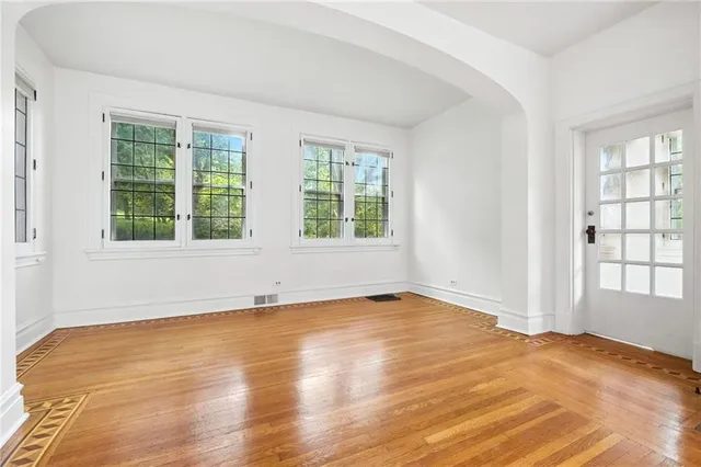an empty room with wooden floor and windows