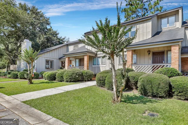 a front view of a house with a yard and green space