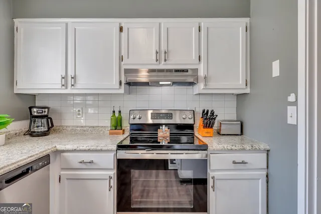 a kitchen with granite countertop white cabinets and stainless steel appliances