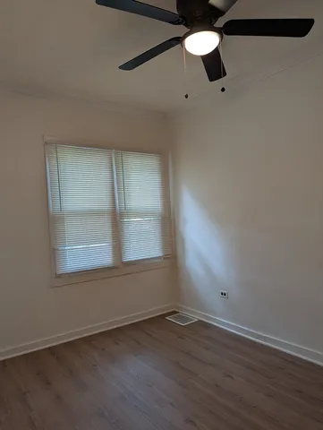 an empty room with wooden floor fan and windows