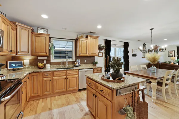 a kitchen with granite countertop stainless steel appliances a refrigerator a stove top oven a sink and cabinets