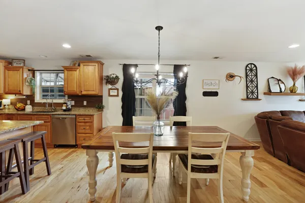 a kitchen with stainless steel appliances kitchen island granite countertop a refrigerator a stove a sink a dining table and chairs with wooden floor