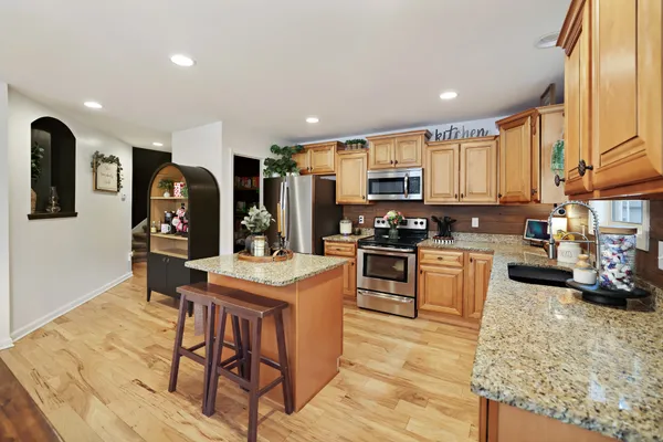 a kitchen with stainless steel appliances granite countertop a stove top oven a sink refrigerator and cabinets