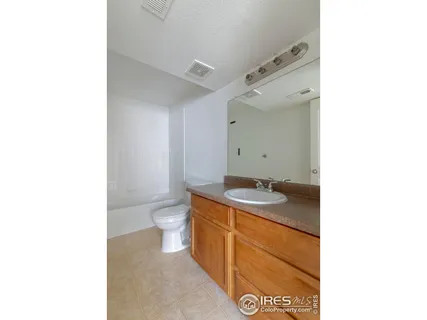 a bathroom with a granite countertop sink a toilet and a mirror