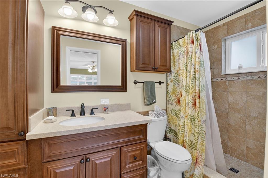 572 High Point Drive, Unit D Delray Beach, FL 33445 - Photo 13 of 21 a bathroom with a toilet a sink and a mirror