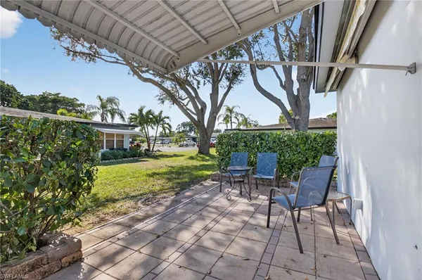 a view of a house with a yard and potted plants and large trees