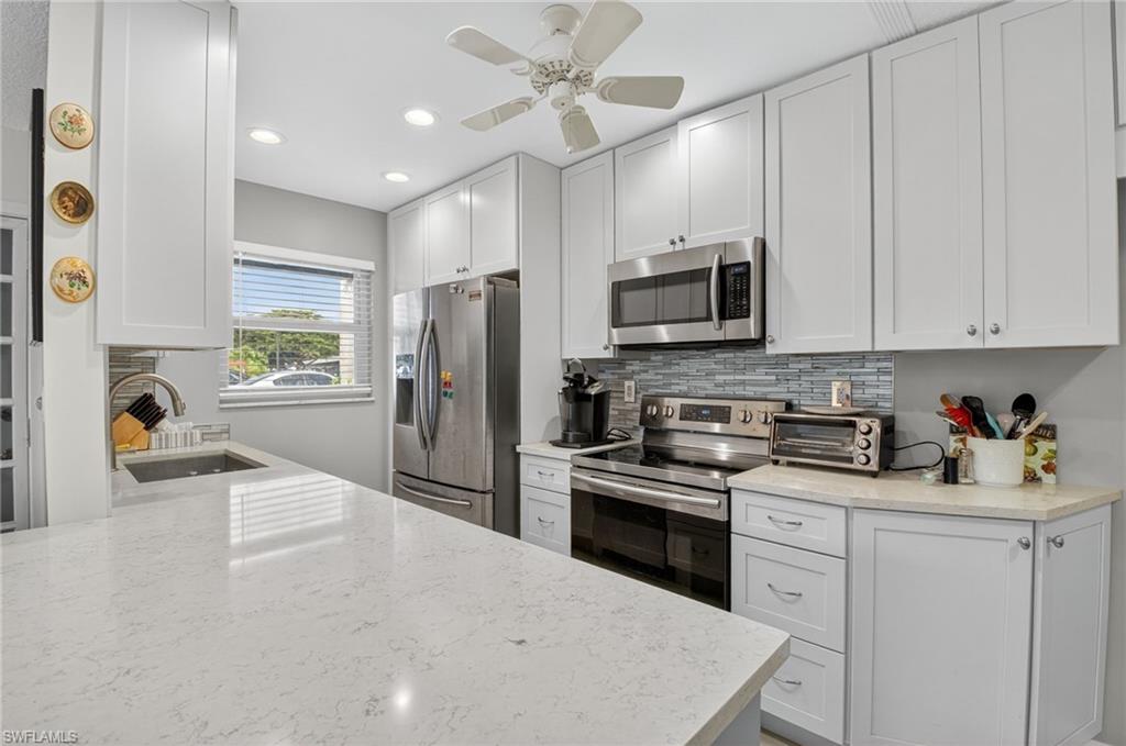 572 High Point Drive, Unit D Delray Beach, FL 33445 - Photo 6 of 21 a kitchen with a refrigerator a stove a sink and a microwave