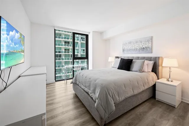a bedroom with a large bed and a flat tv screen on dresser