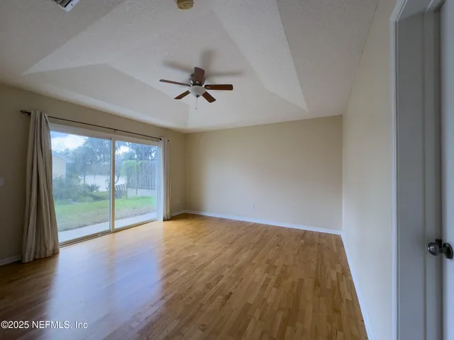 a view of empty room with wooden floor and fan