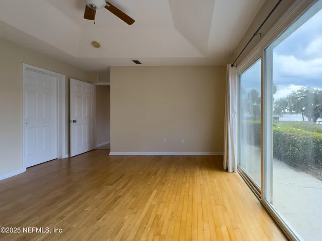 a view of empty room with wooden floor and fan