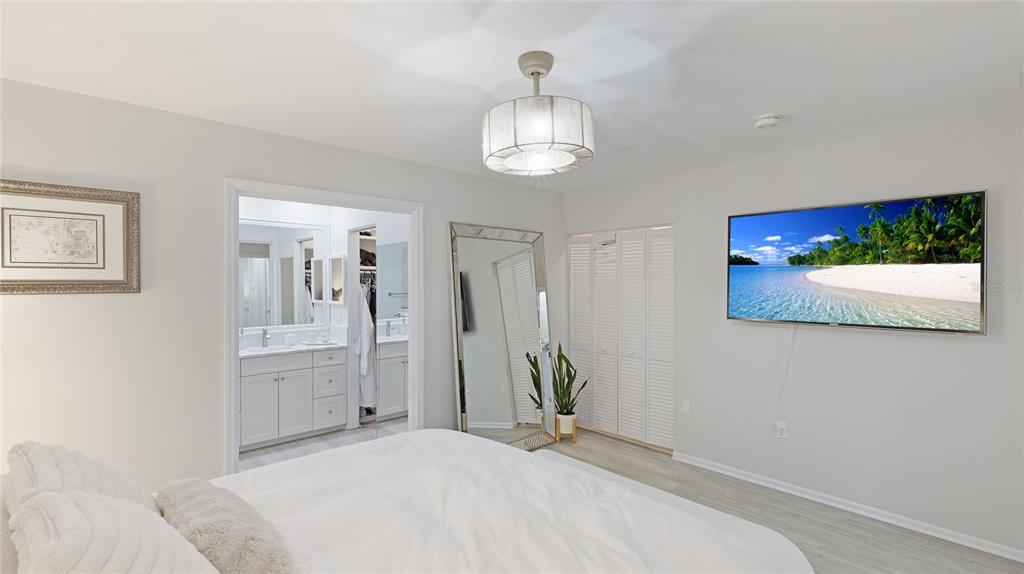 6726 South Lockwood Ridge Road Sarasota, FL 34231 - Photo 19 of 36 a bedroom with a bed and a chandelier