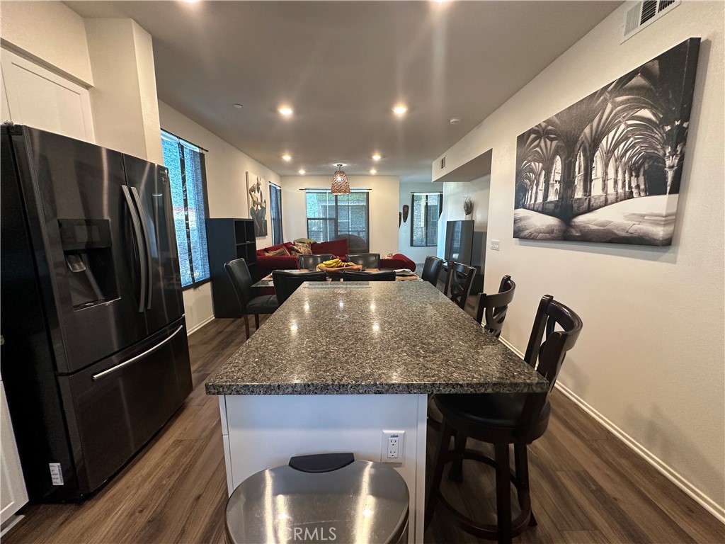 17612 Garden House Lane Bellflower, CA 90706 - Photo 5 of 31 a kitchen with stainless steel appliances granite countertop a table chairs and a refrigerator