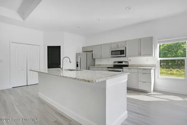 a kitchen with granite countertop white cabinets and stainless steel appliances