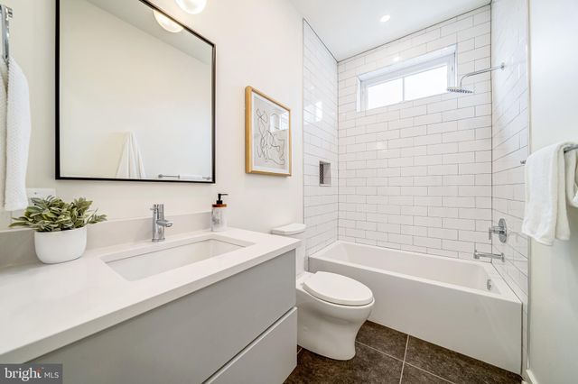 a bathroom with a bathtub shower sink vanity mirror and toilet