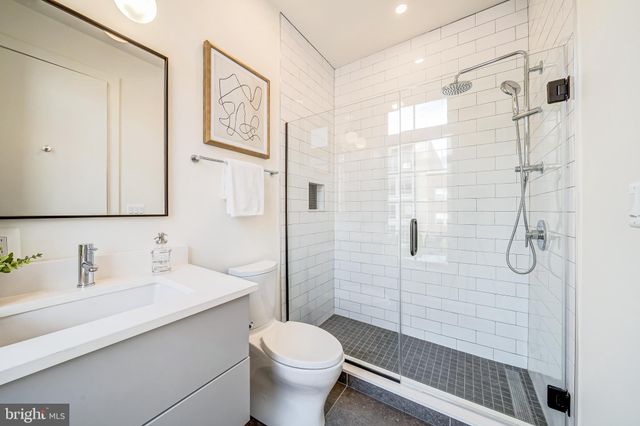 a bathroom with a shower sink vanity mirror and toilet