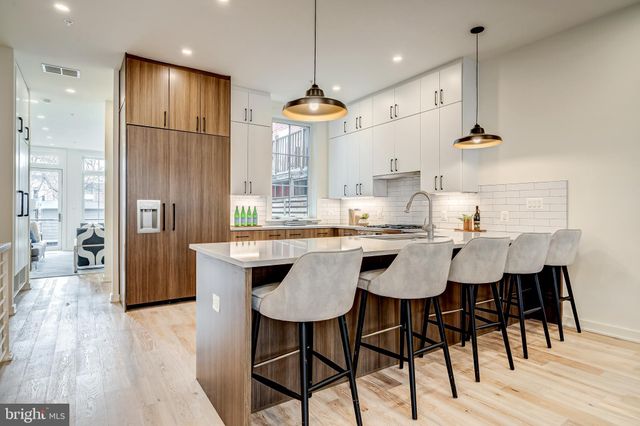 a kitchen with stainless steel appliances granite countertop a table chairs stove and wooden floor