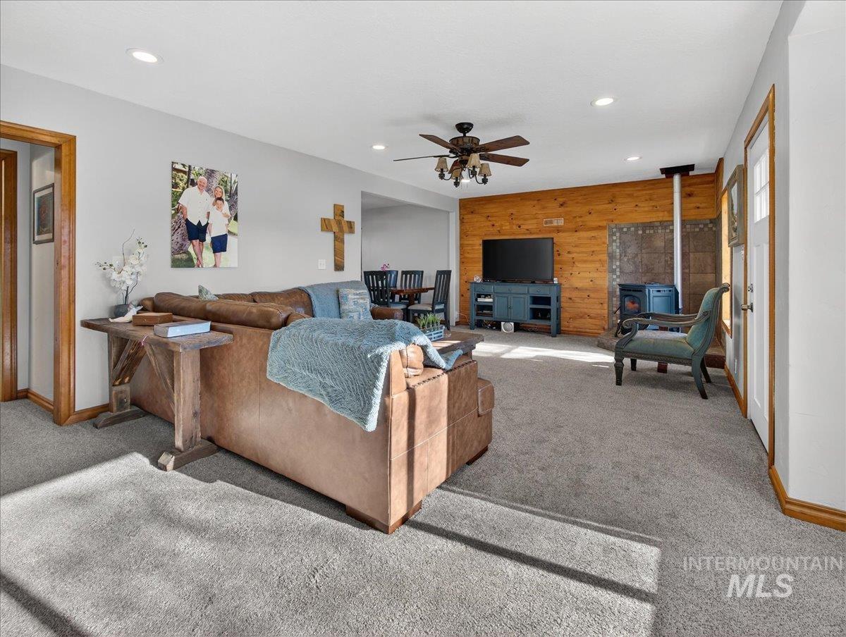 2588 West Sales Yard Road Emmett, ID 83617 - Photo 14 of 49 Living area with a wood stove, wooden walls, an accent wall, carpet flooring, and recessed lighting