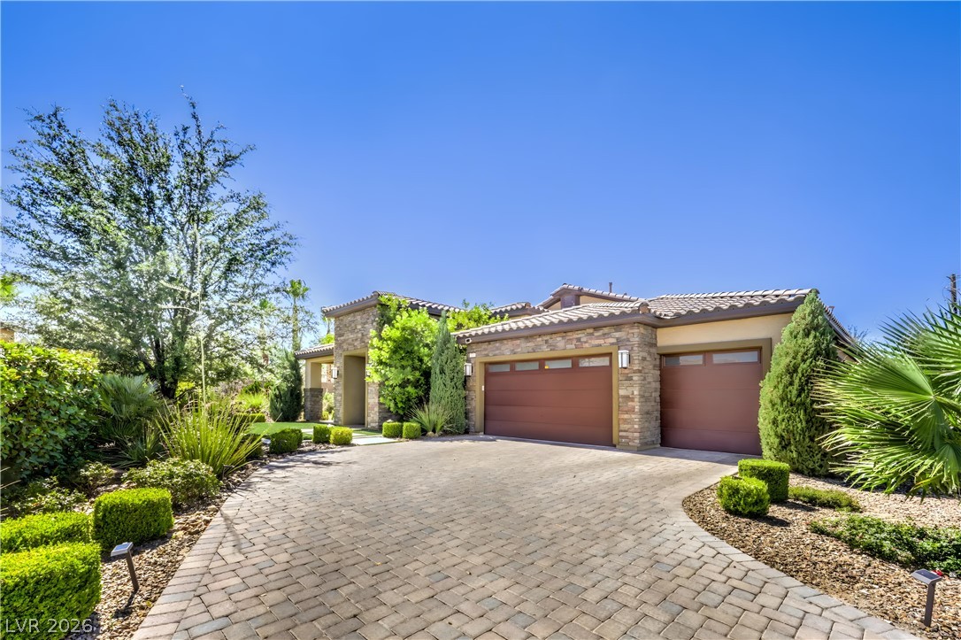 7119 Arabian Ridge Street Las Vegas, NV 89131 - Photo 5 of 73 A grand paver driveway leads to a striking home adorned with stone accents and lush landscaping.