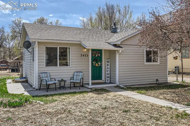 a view of a brick house with many windows plants and large tree