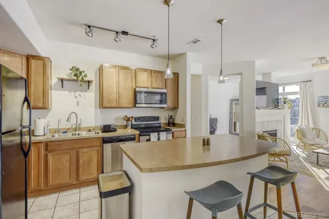 a kitchen with stainless steel appliances granite countertop a sink a stove and chairs